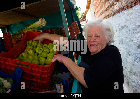 Greek old village woman with white hair dressed in black is buying green peppers from a costermonger Stock Photo