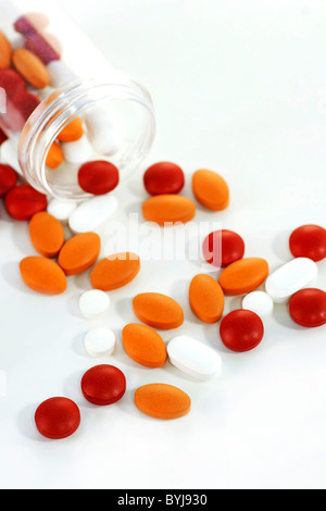 High key of plastic bottle and spilled out pills of different colors Stock Photo