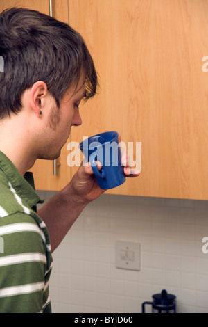 Young single man, 20s, in kitchen drinking coffee Stock Photo
