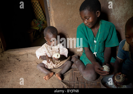 A family shares a meal together in their mud home in Masaka, Uganda, East Africa. Stock Photo