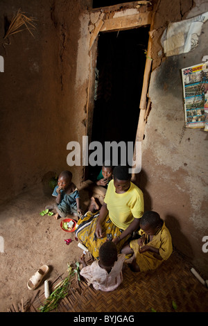 A family shares a meal together in their mud home in Masaka, Uganda, East Africa. Stock Photo