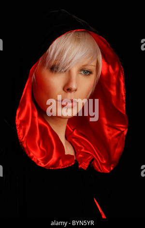 young silver haired woman wearing a red lined black cloak Stock Photo