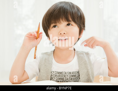 Boy Sitting Table Holding Pencil Thinking Stock Photo
