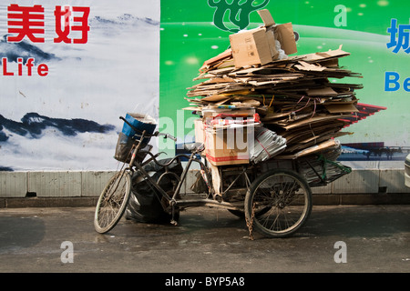 Tricycle stacked with cardboard boxes in front of a wall Stock Photo