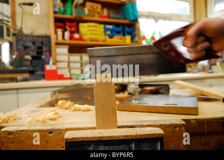 Man sawing through a piece of wood in a trainee woodwork 
