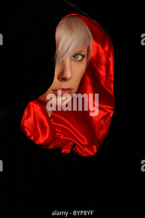 young silver haired woman wearing a red lined black cloak Stock Photo