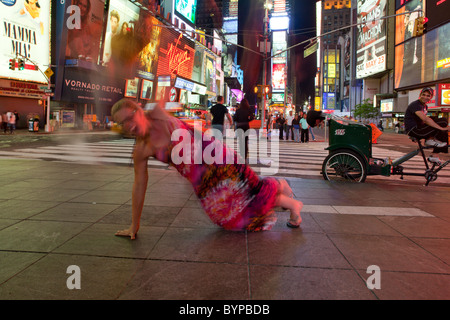 USA, New York, New York City, Blurred image of woman dancing and posing for snapshots under brightly lit signs of Times Square Stock Photo