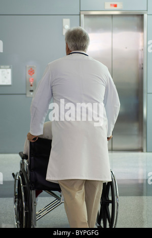 Doctor pushing patient in wheelchair Stock Photo