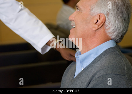 Healthcare worker reassuring man in waiting room Stock Photo