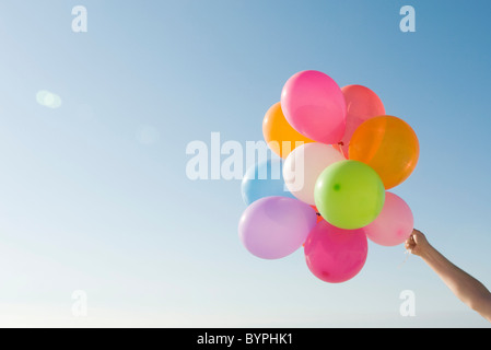 Bunch of helium balloons held aloft against clear blue sky Stock Photo
