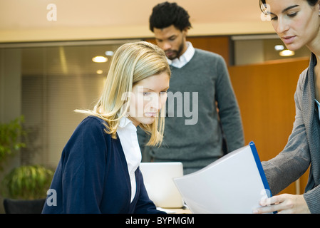 Female office worker showing document to colleague Stock Photo