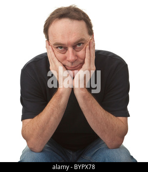 adult man sat with his head in his hands glancing upwards, he is casually dressed and isolated against a white background Stock Photo