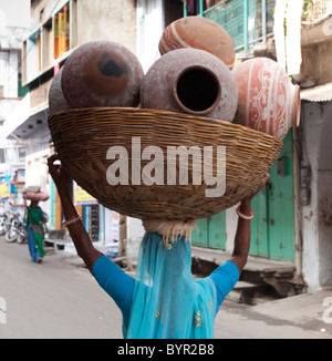 India, Rajasthan, Udaipur, woman carrying water pots in wicker basket Stock Photo