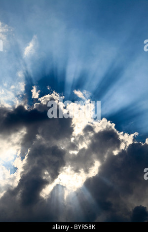 Sun rays emerging from behind a cumulus cloud on a bright summers day Stock Photo