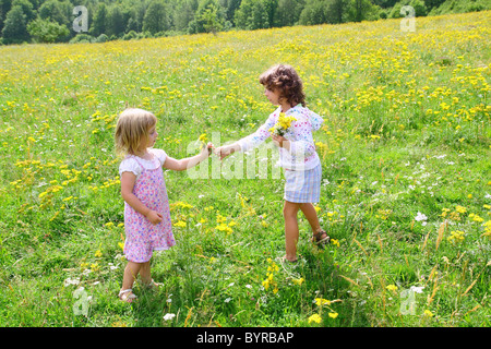 sister girls in meadow playing with spring flowers outdoor Stock Photo