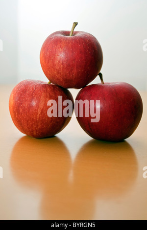 Three red apples balanced on top of each other with shadow underneath Stock Photo