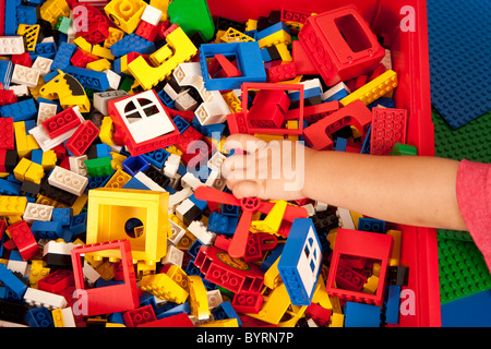 Child reaches for a building block piece. Stock Photo