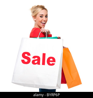 Attractive young woman looking happing holding shopping bags displaying the sale sign Stock Photo