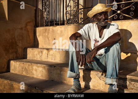 Old man with a cigar sitting down in the street, Trinidad, Sancti Spiritus, Cuba, Caribbean Stock Photo