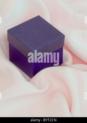 Small square closed purple gift  box and lid on pink silk Stock Photo