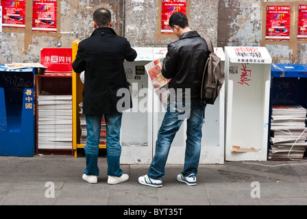 Two men reading Chinese newspapers on Gerrard St, London which is the main street of Londons famous Chinatown. Stock Photo