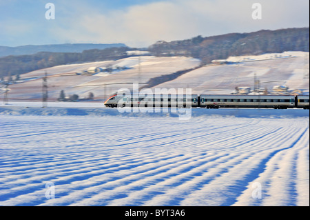 A Swiss train speeding through a snowy landscape in mid-winter. Motion blur used to give sense of speed. Stock Photo