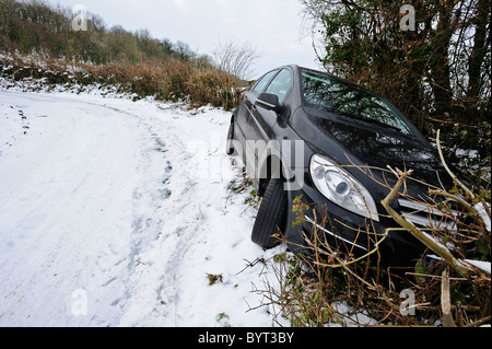 Car in the ditch. A car crashed into the hedge on the bend of an icy, snow-covered road. Stock Photo