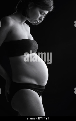Five Month Pregnant Lady against Black Background Stock Photo