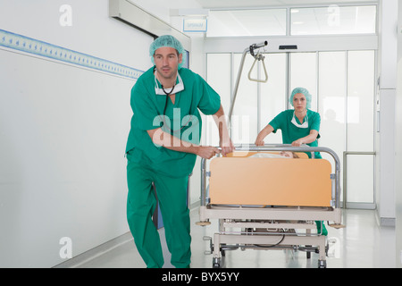 Medical team in scrubs with bed in hall Stock Photo