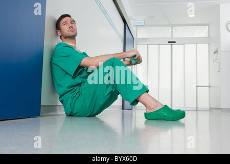 Doctor in scrubs, resting on the floor Stock Photo