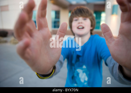 Eleven year old boy reaching his hands out to camera, begging for something. Stock Photo