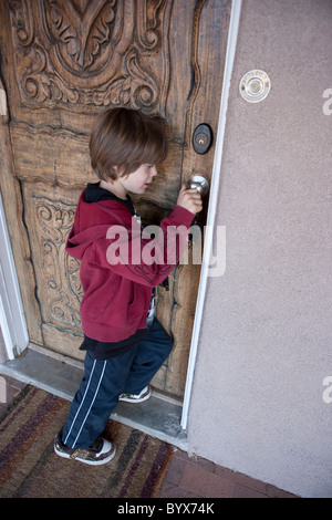 Seven year old child using a key to unlock and open his house front door Stock Photo