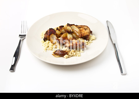 Moroccan Spiced Chicken with couscous and onions isolated on white. Stock Photo