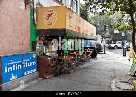 old fashioned outdoor seating at Mexican chicken restaurant with sidewalk pinball machine Roma district Mexico City Stock Photo