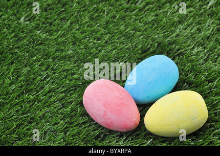 Three colorful Easter eggs on green grass with copy space. Stock Photo