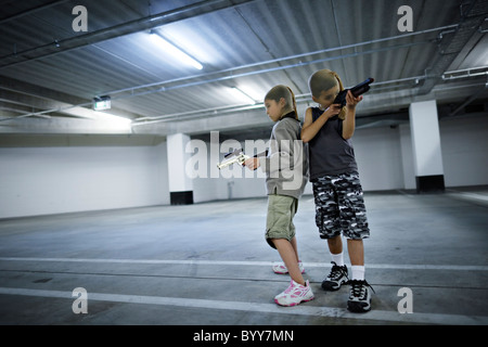Children with stocking masks and toy guns in underground carpark prepare for big hold-up. Stock Photo