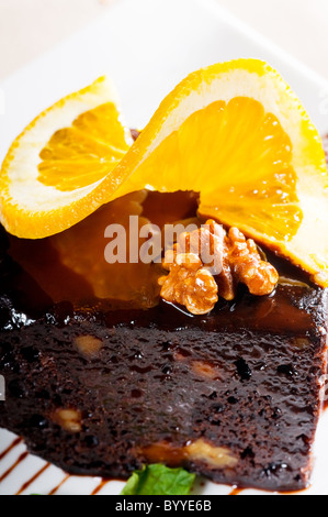 fresh baked delicious chocolate and walnuts cake with slice of orance on top Stock Photo