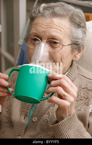 elderly woman using a steam inhaler inhaling a decongestant for colds & bronchitis Stock Photo