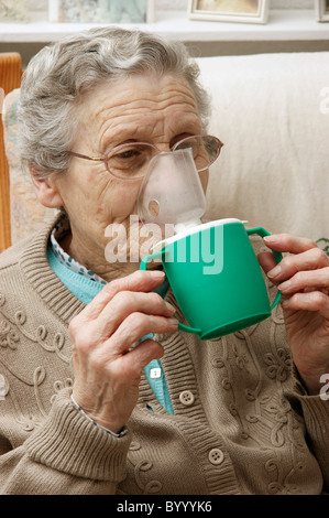 elderly woman using a steam inhaler inhaling a decongestant for colds & bronchitis Stock Photo