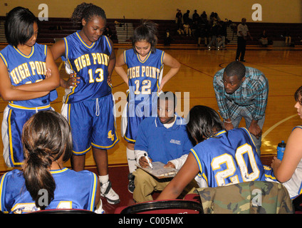 Coach discusses strategy with his players at a girl's high school basketball game Stock Photo