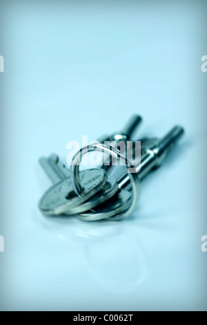 A Yale key and two mortice lock keys on a worn metal key ring set against a blue background. Stock Photo