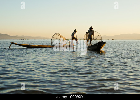 Intha leg-rowing fishermen with basket nets on Inle Lake at sunset, Myanmar (Burma) Stock Photo