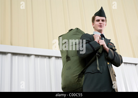 Young man in retro army uniform carrying duffel bag Stock Photo