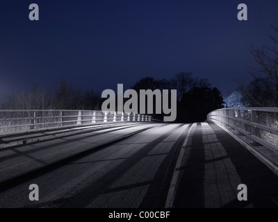 Road and trees lit by street lights at night with blue sky , taken by roadside locations Stock Photo