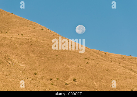 A full moon hovers over the Zagros Mountains near the Kurdish village of  Bahcesaray, in the eastern Anatolia region of southeastern Turkey. Stock Photo