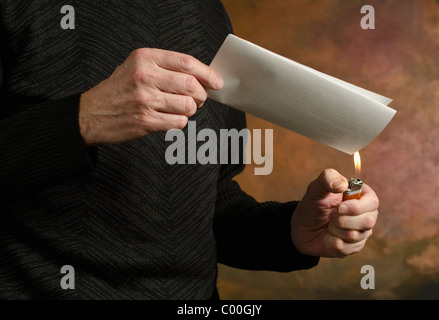 man holding butane lighter to folded document Stock Photo