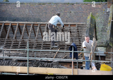 Builders repairing roof on old house England Uk Stock Photo