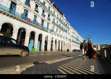 Algeria, Alger, couple walking on sidewalk while car moving on street by residential structure Stock Photo