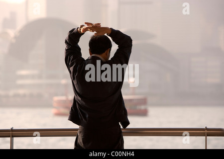 China, hong kong, early morning in town with man doing Tai Chi exercises before work Stock Photo