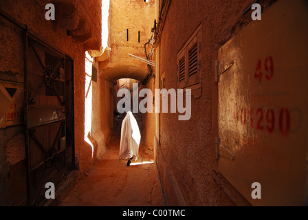 Algeria, Ghardaia, person walking on alley between houses, face covered with cloth Stock Photo